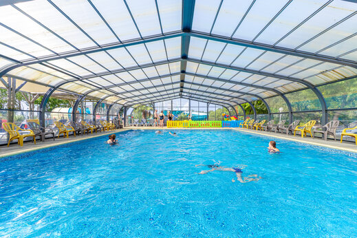 Beheiztes Hallenbad mit Badegästen und Stühlen auf dem Campingplatz CAPFUN L'Eve in Saint-Marc-sur-Mer (44).