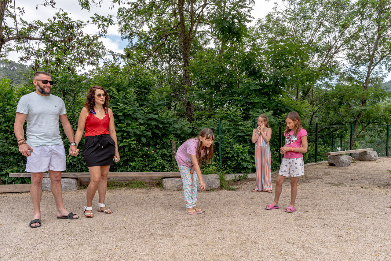 Familie speelt jeu de boules op het speelterrein van camping CLICOCHIC Eyrieux in Les OLLIERES-SUR-EYRIEUX.