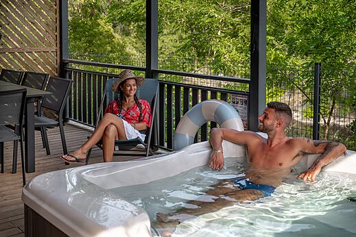 Paar entspannt im privaten Whirlpool auf Terrasse auf Camping CLICOCHIC Eyrieux.