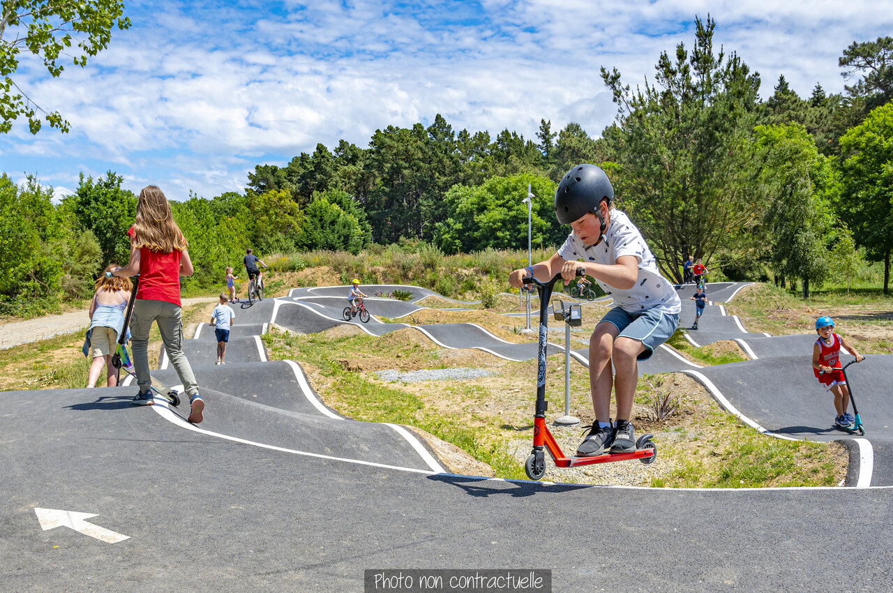 Kinder auf Pumptrack mit Rollern und Fahrr�dern auf dem Campingplatz CAPFUN Falaises in Gonneville sur Mer.