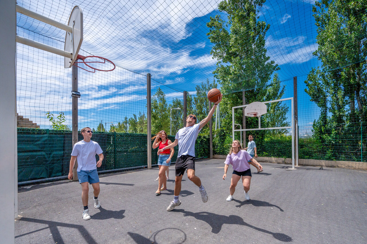 Young people playing basketball on multisport court at CAPFUN F�erix MARSEILLAN PLAGE.