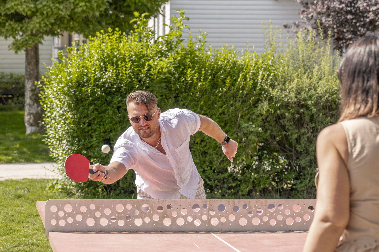 Couple playing outdoor table tennis at CLICOCHIC Ferme des Aulnes campsite.