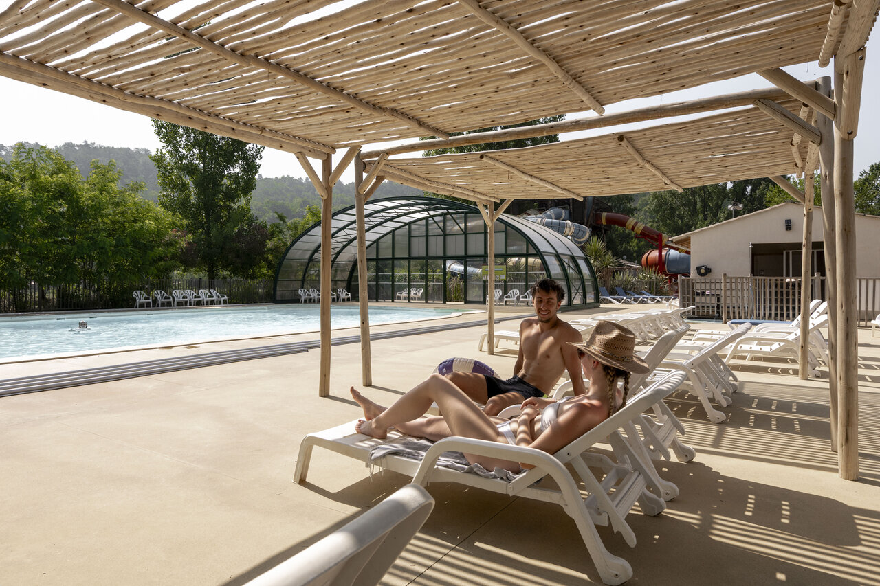 Couple se relaxant pr�s de la piscine avec toboggans au camping CLICOCHIC Filament � Thoiras (30).