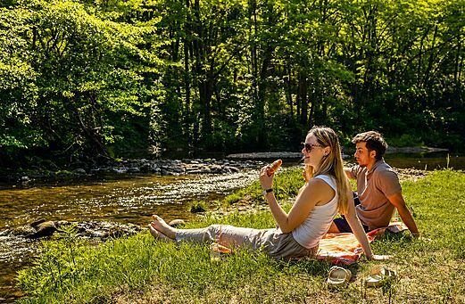 Koppel ontspant aan de oever van een natuurlijke rivier op camping CLICOCHIC Filament in Thoiras (30).