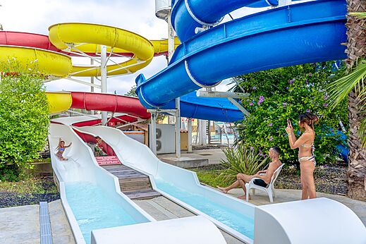 Bunte Wasserrutschen und Kind beim Rutschen auf dem Campingplatz CAPFUN Fleurs d'Agde in AGDE (34).