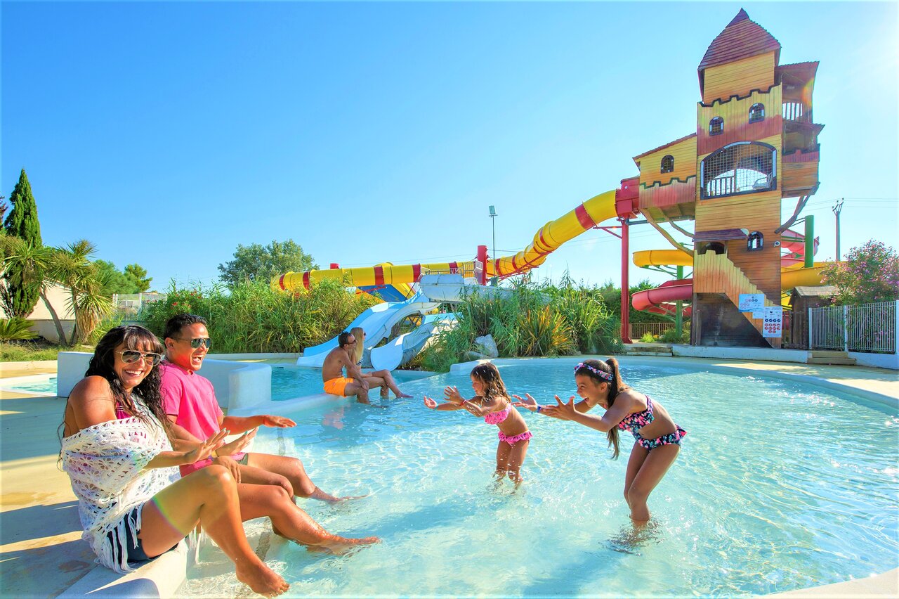 Schwimmbad mit Wasserrutschen, Burgstruktur und Familie auf dem Campingplatz CAPFUN Fleur de Camargue in Saint-Laurent-d Aigouze (30).