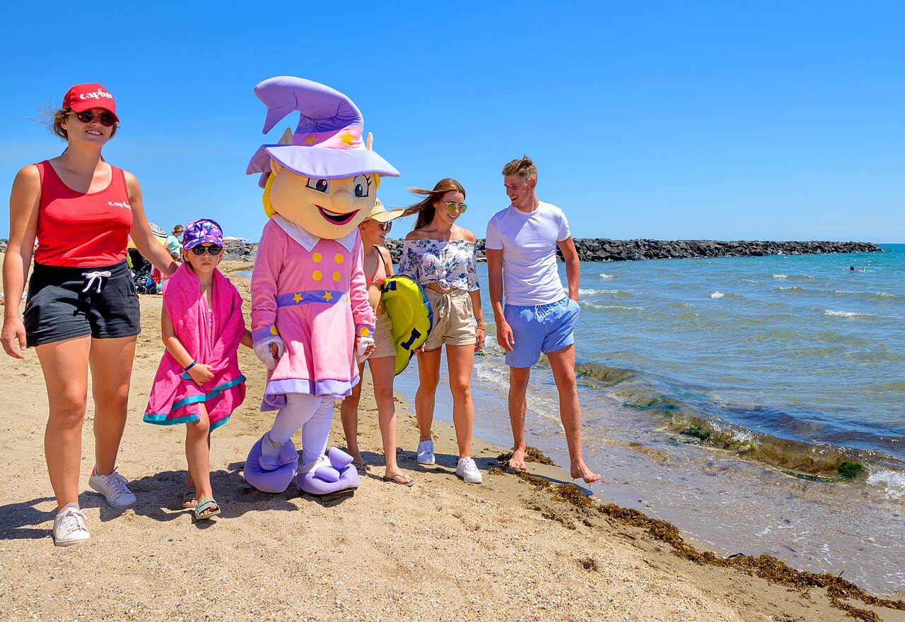 Maskottchen und Urlauber am Strand des CAPFUN Flots Bleus Campingplatzes, VIAS PLAGE.