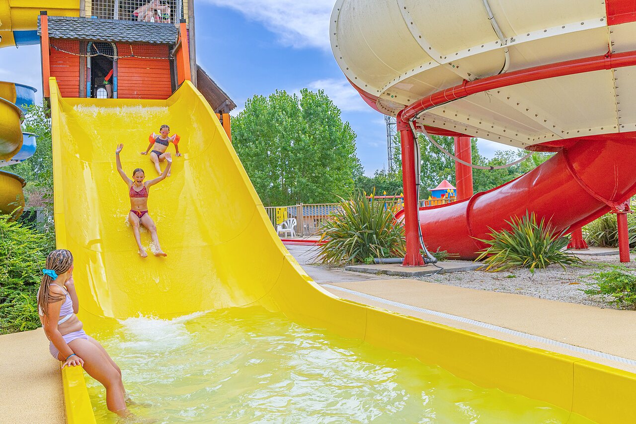Gelbe Wasserrutsche und Pool mit Kindern auf dem Campingplatz CAPFUN Forges in Avrille (85).