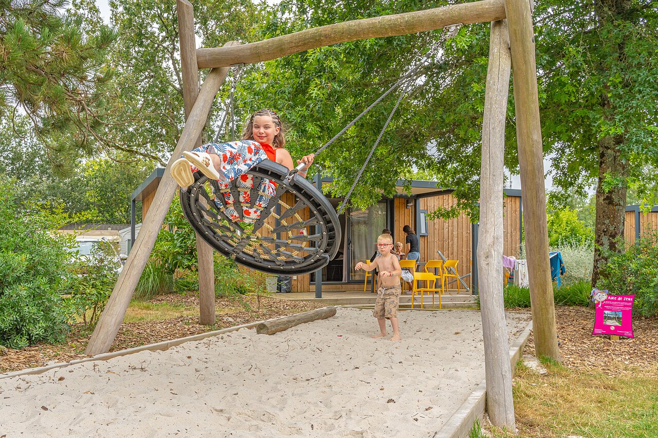 Kinder spielen auf Nestschaukel und Sandkasten am Campingplatz CAPFUN Forges in Avrille (85).