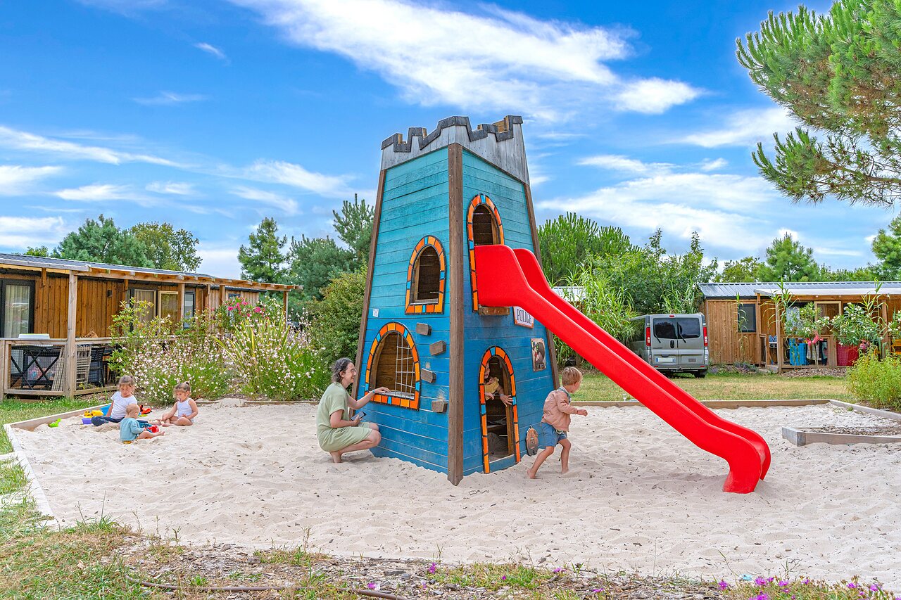 Spielplatz mit Holzturm, Rutsche und Sandkasten auf dem Campingplatz CAPFUN Forges in Avrille (85).