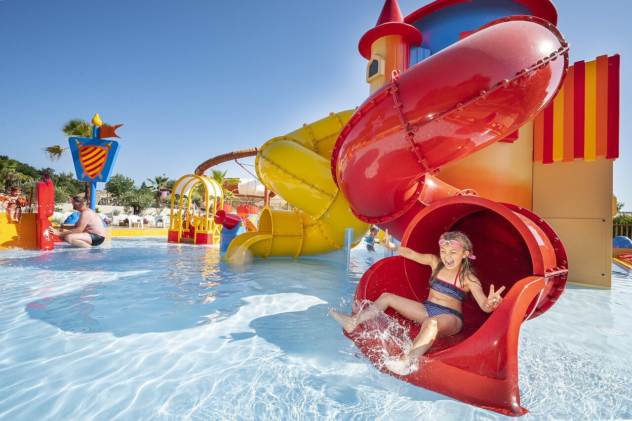 L�chelndes M�dchen rutscht rote Wasserrutsche im Pool auf Camping CAPFUN Forges in Avrille (85).