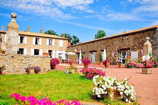 Steingeb�ude, Rezeption und bl�hende Restaurantterrasse auf dem Campingplatz CAPFUN Forges in Avrille (85).