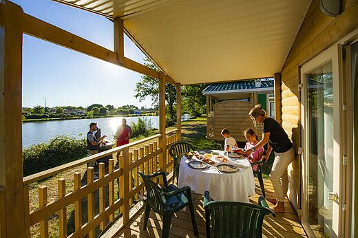 Mobilheim-Terrasse, Familie beim Mittagessen, Grillen am See auf dem Campingplatz CAPFUN Forges in Avrille (85).