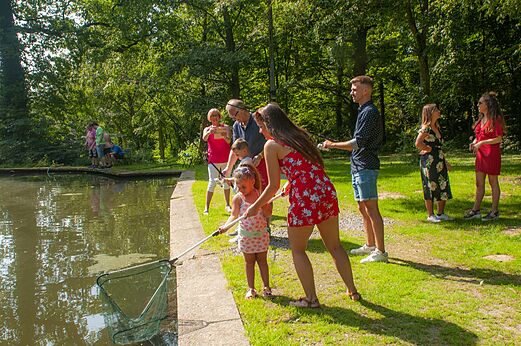 Famille pêchant avec cannes et épuisette au bord d'un étang au camping CAPFUN Fort Bedmar à Sint-Gillis-Waas.