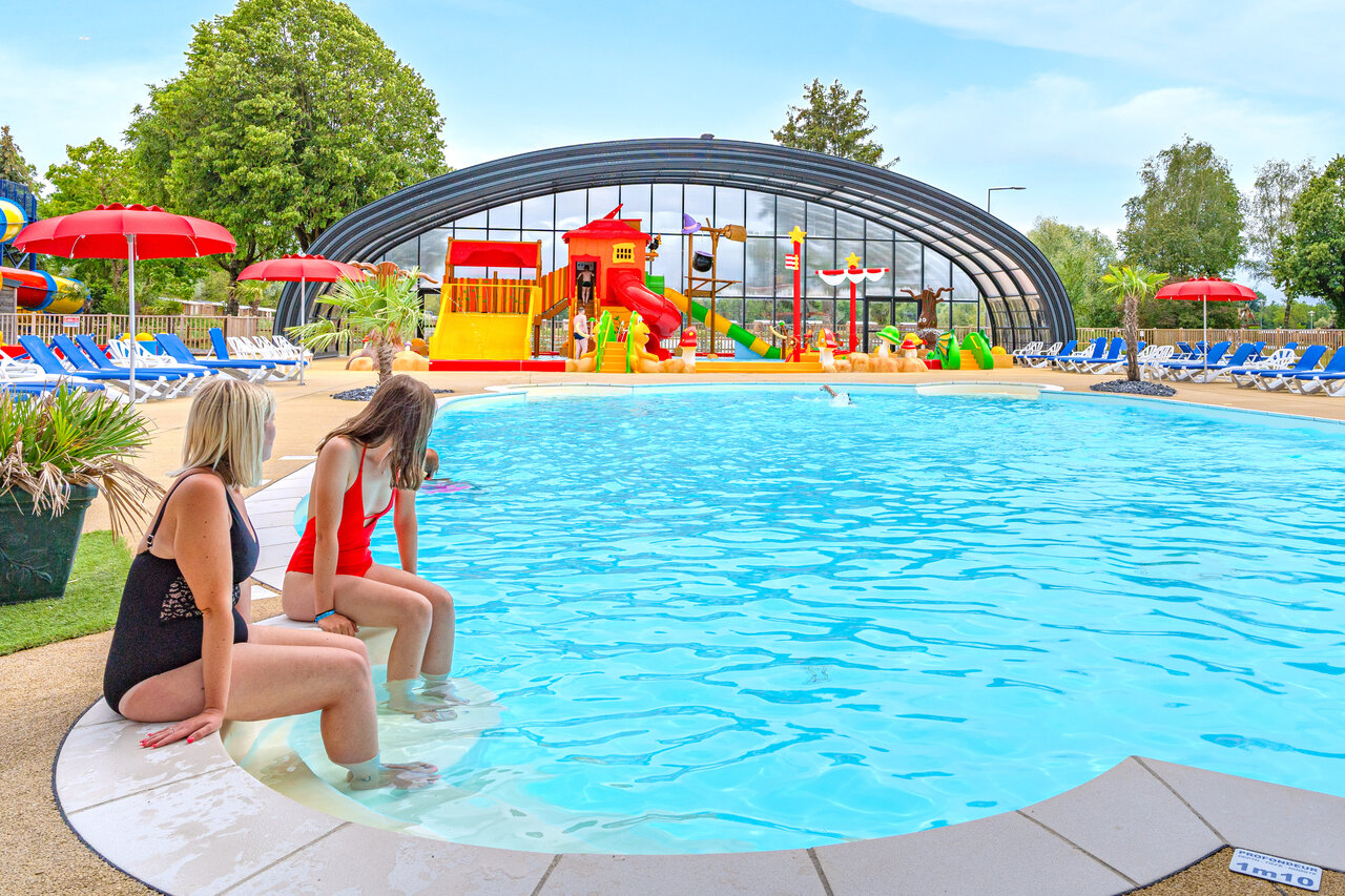 Zwei Frauen am Pool mit Wasserspielen im Camping CAPFUN Fort Falabraque in Seltz (67).