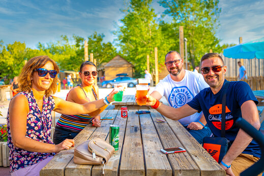 Vrienden proosten met drankjes aan de bar van camping CAPFUN Fort Falabraque, Seltz.