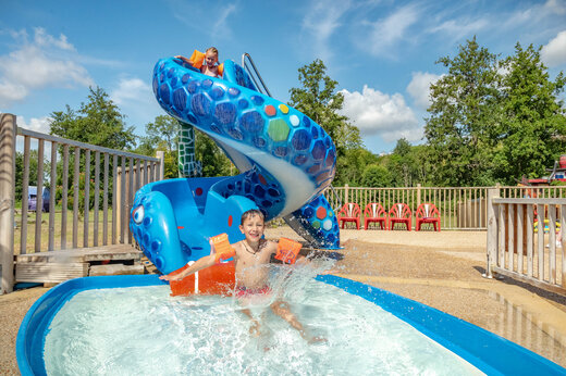 Lustige Wasserrutsche und Kinder spielen im Pool auf dem Campingplatz CAPFUN Fredland in Tournan en Brie (77).