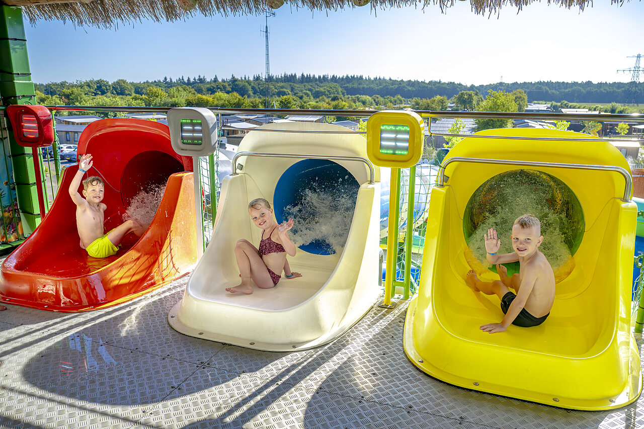 Lachende Kinder auf den farbenfrohen Wasserrutschen des Campingplatzes CAPFUN De Fruithof in Klijndijk.