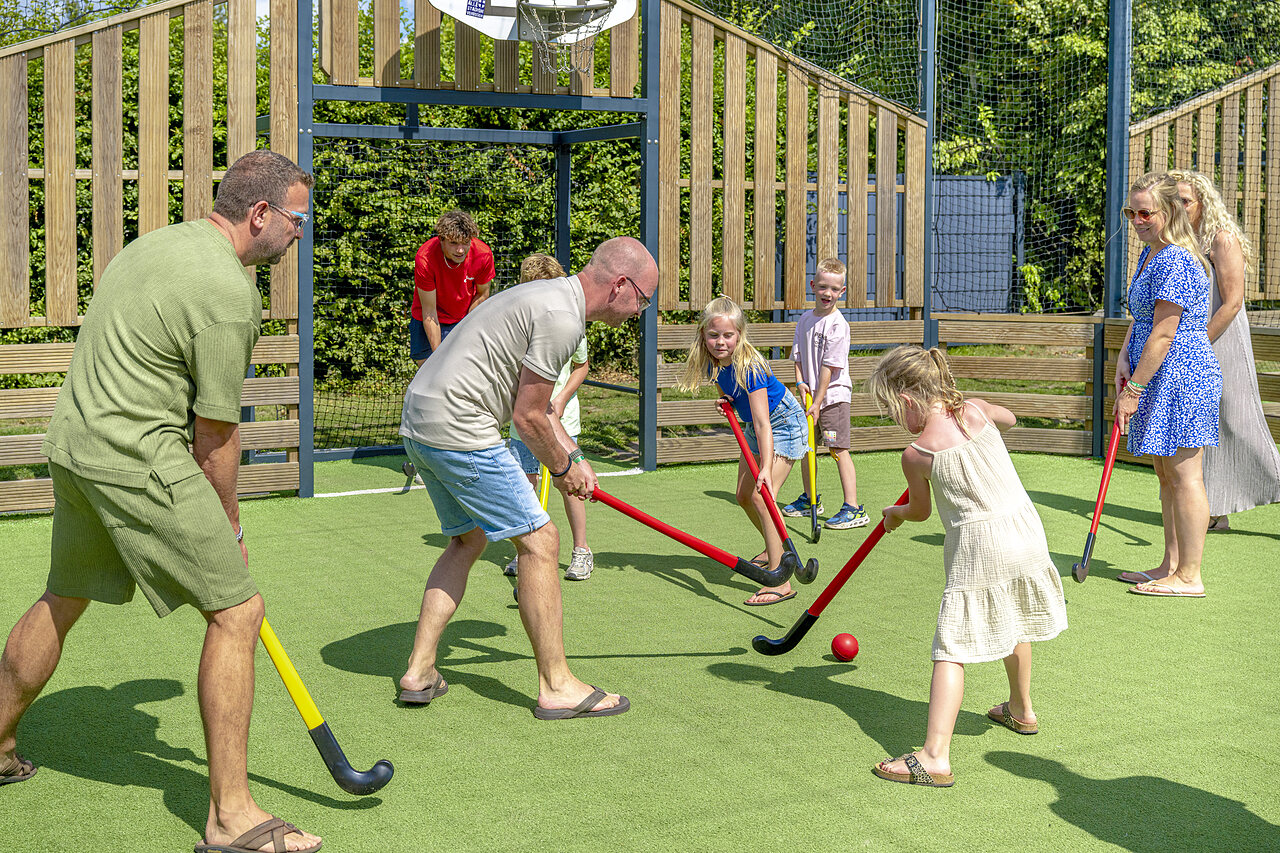 Familie spielt Hockey auf Kunstrasenplatz auf dem Campingplatz CAPFUN De Fruithof in Klijndijk.