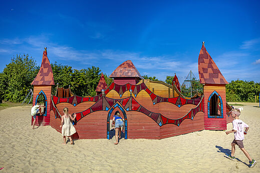 Hölzernes Spielschloss auf Sand für Kinder auf dem Campingplatz CAPFUN De Fruithof in Klijndijk.
