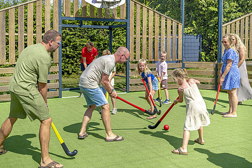 Familie spielt Hockey auf Sportplatz beim Camping CAPFUN De Fruithof in Klijndijk.