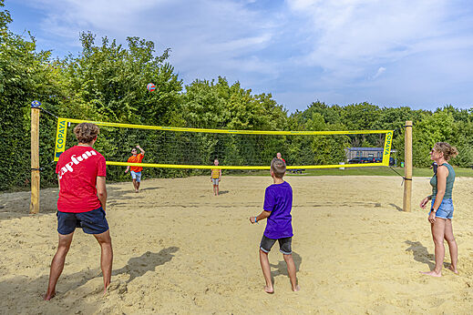 Sand-Beachvolleyballfeld mit Spielern auf dem Campingplatz CAPFUN De Fruithof in Klijndijk.