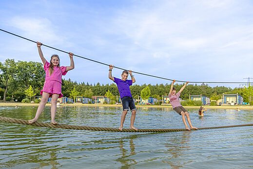 Kinder spielen auf einem Wasserparcours auf dem Campingplatz CAPFUN De Fruithof in Klijndijk.