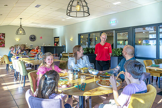 Familie speist fröhlich im Restaurant des Campingplatzes CAPFUN De Fruithof in Klijndijk.