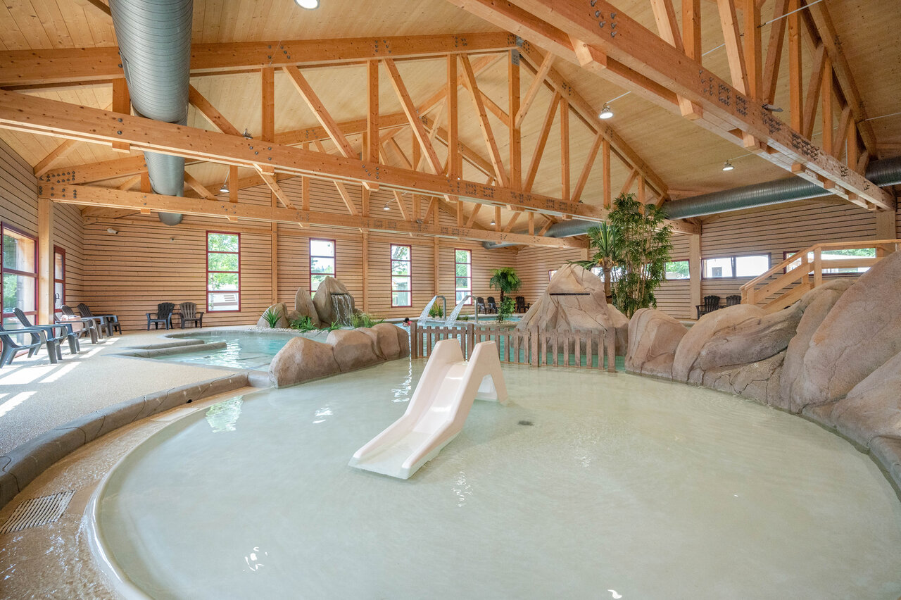 Indoor swimming pool with slide and water games at CAPFUN Fuvettes campsite in Malbuisson (25).