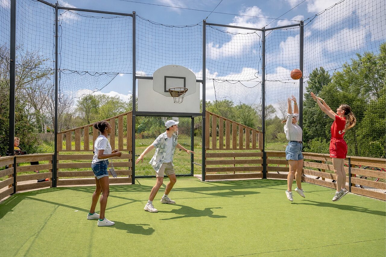Multisportplatz mit Jugendlichen beim Basketballspielen auf dem Campingplatz CAPFUN Golf in SAINT JEAN DE LA RIVIERE (50).