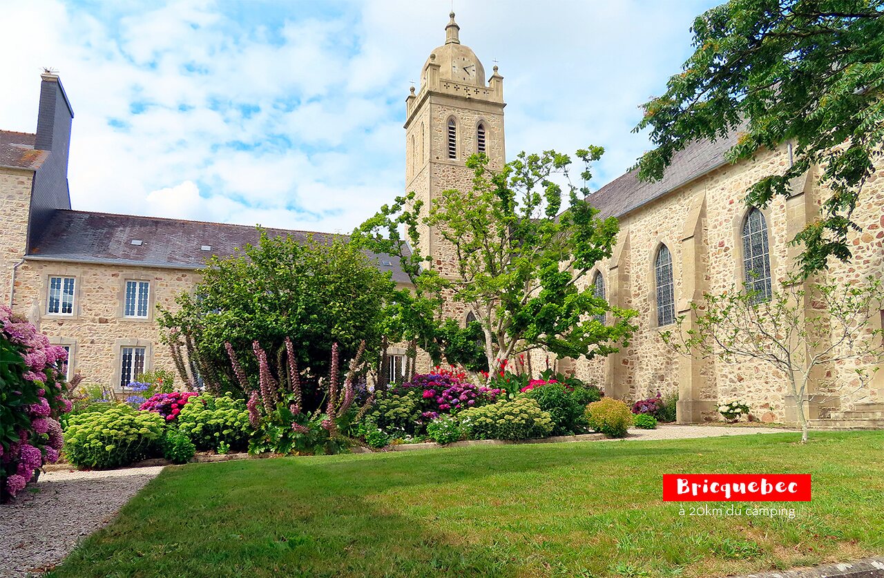 Historische Kirche von Bricquebec mit Glockenturm und Blumengarten, in der Normandie.