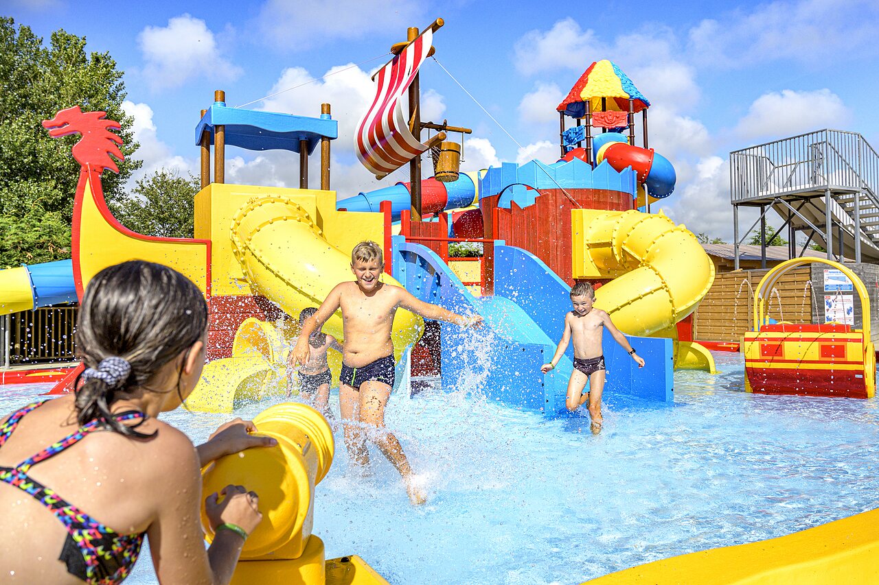 Wasserpark mit Rutschen, Wasserspielen und lachenden Kindern auf Camping CAPFUN Golf in SAINT JEAN DE LA RIVIERE (50).