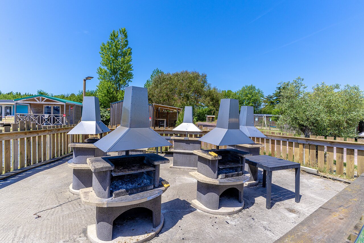 Gemeinschaftlicher Grillplatz mit mehreren Grills auf dem Campingplatz CAPFUN Golf in SAINT JEAN DE LA RIVIERE (50).