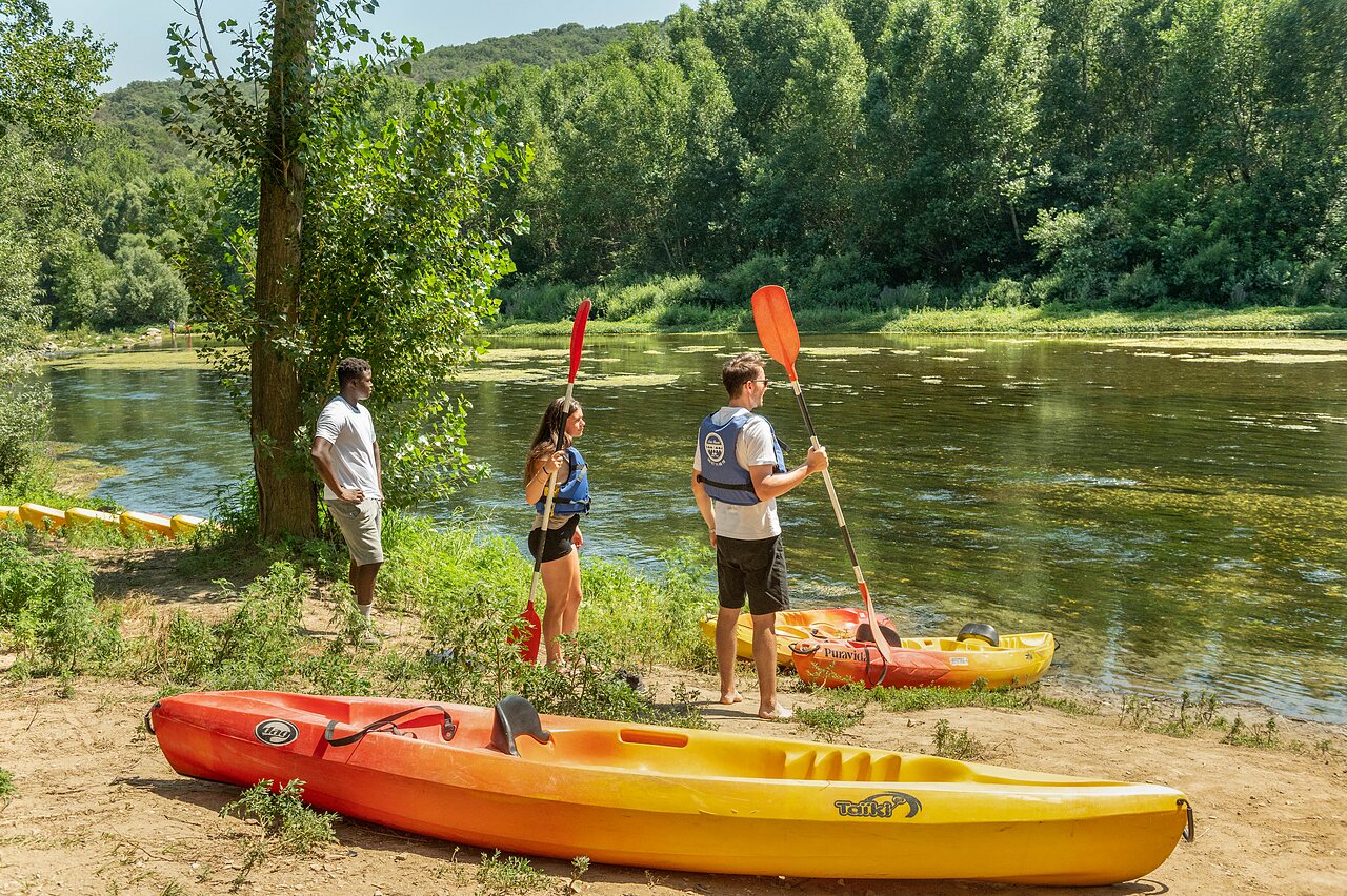 Personen mit Kajaks und Paddeln am Flussufer auf dem Campingplatz CLICOCHIC Gorges du Gardon in VERS PONT DU GARD (30).
