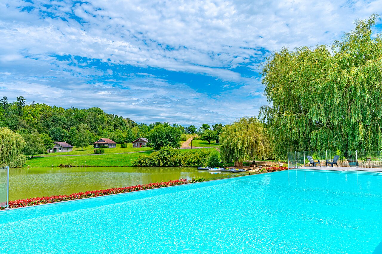 Piscina infinita, lago y chalets en el camping CAPFUN Grand Cerf en Gimouille (58).