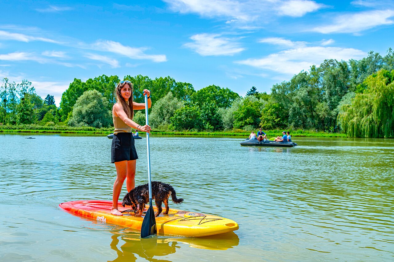 Mujer y perro en paddle surf en el lago del camping CAPFUN Grand Cerf en Gimouille (58).