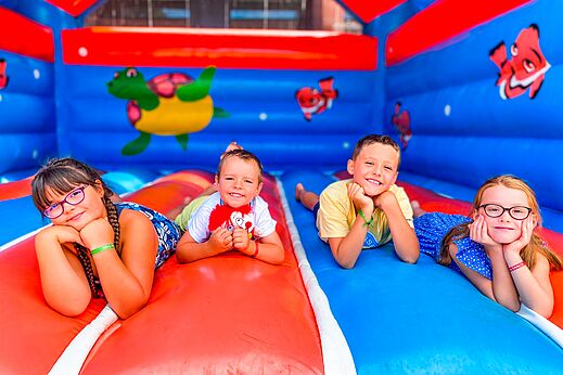 Vier lachende kinderen op kleurrijk opblaasbaar spel op camping CAPFUN Grand Cerf in Gimouille (58).