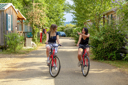 Deux femmes à vélo sur allée, au camping CAPFUN Grand Lierne à CHATEAUDOUBLE (26).