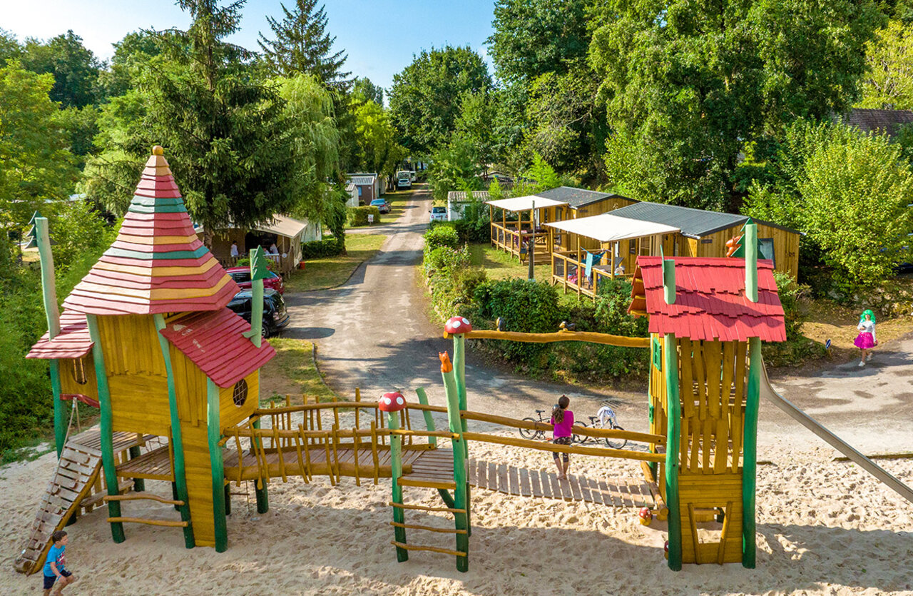 Wooden playground with slide and sand at VAGUES OCEANES Granges campsite in GROLEJAC (24).