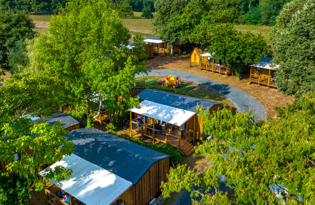 Wooden chalets with terraces, aerial view of VAGUES OCEANES Granges campsite in GROLEJAC (24).