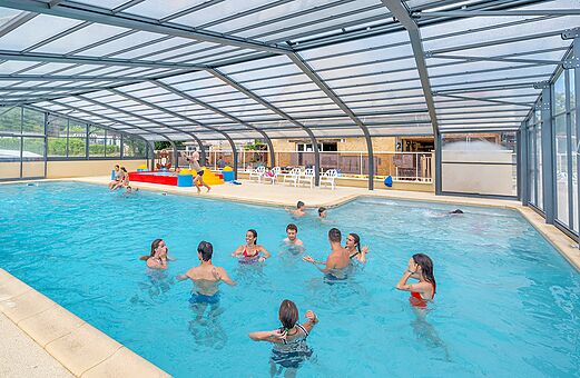 Überdachtes Schwimmbad mit Badegästen auf Camping VAGUES OCEANES Granges in GROLEJAC.