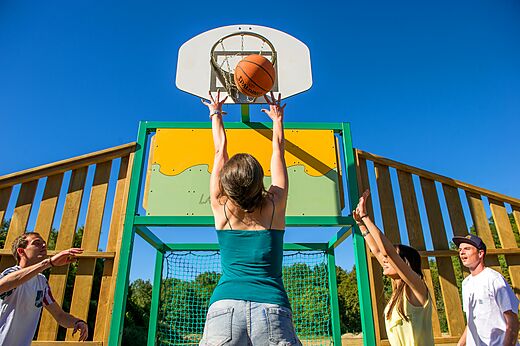 Jongeren basketballen op het sportterrein van camping CLICOCHIC Grisière.