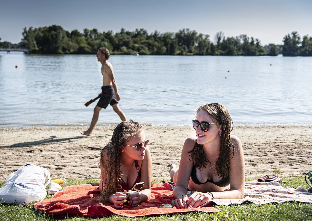 Zwei junge Frauen entspannen am Strand des Campingplatzes CAPFUN Groene Eiland Appeltern.
