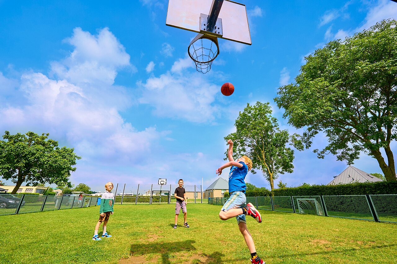 Kinder spielen Basketball auf Multisportplatz auf dem Campingplatz CAPFUN Groene Eiland in Appeltern.