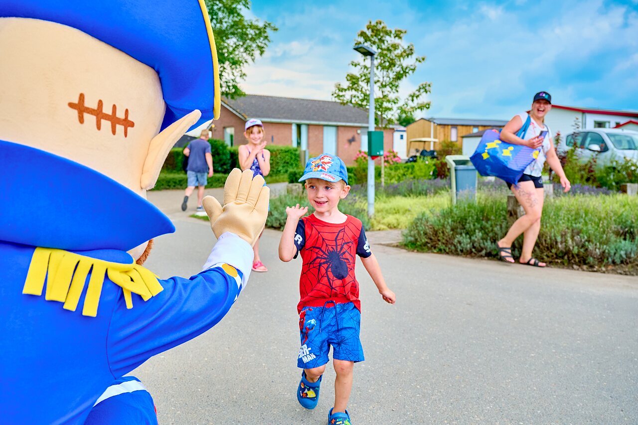 Maskottchen winkt l�chelndem Kind bei Animation auf Campingplatz CAPFUN Groene Eiland in Appeltern.