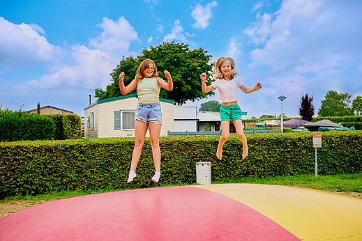 Zwei Kinder springen auf einem riesigen H�pfkissen auf Camping CAPFUN Groene Eiland in Appeltern.