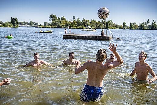 Jugendliche spielen Volleyball im Seewasser auf dem Campingplatz CAPFUN Groene Eiland in Appeltern.