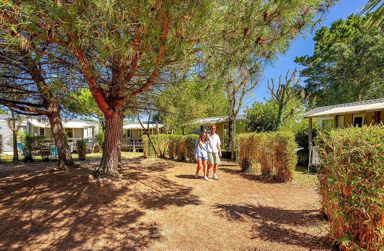 Stel wandelt tussen schaduwrijke stacaravans op camping VAGUES OCEANES Grosses Pierres in Saint-Georges-d'Ol�ron (17).