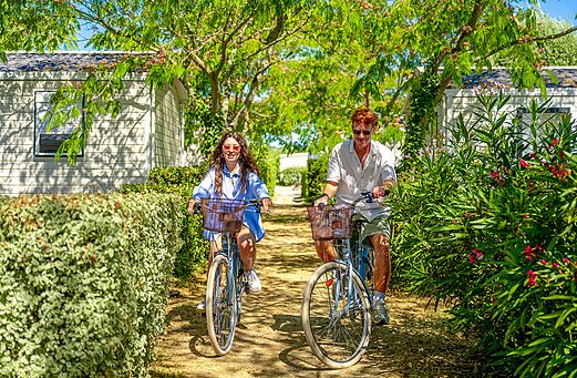 Couple cycling on green path at VAGUES OCEANES Grosses Pierres campsite.