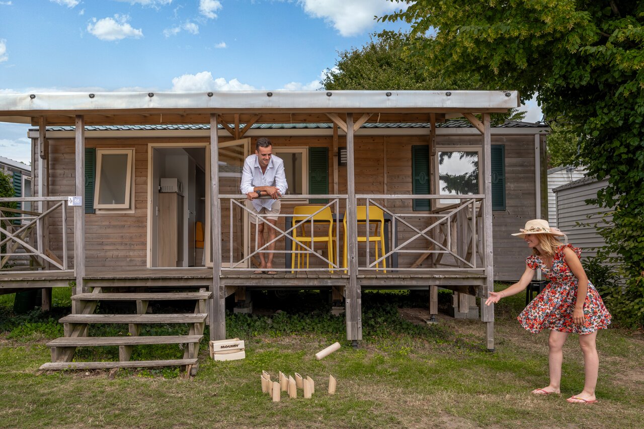 Holz-Mobilheim mit Terrasse, Paar spielt M�lkky auf Camping CLICOCHIC Haras de Deauville in Touques.